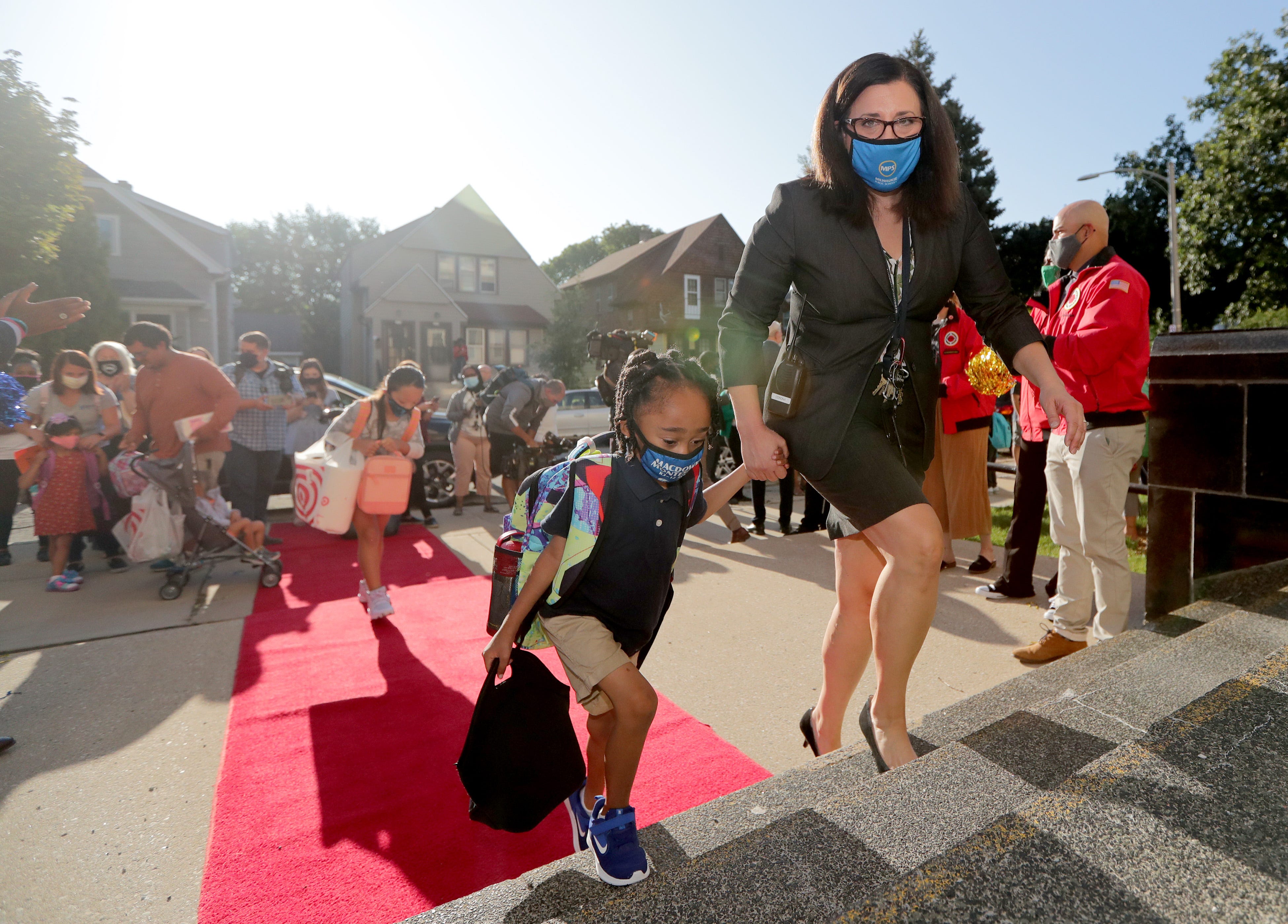 MacDowell Montessori School Principal Andrea Corona walks a student into school during the first day of school at MacDowell Montessori School on Mt. Vernon Avenue in Milwaukee.