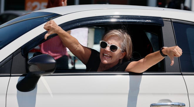 A woman gives the thumbs down to supporters of former President Donald Trump as they rally along Southern Blvd. in West Palm Beach on Monday, April 3, 2023. Trump is expected to be booked and arraigned Tuesday on charges arising from hush money payments during his 2016 campaign.