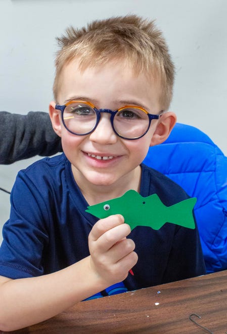 Isaac Krebsbach, 5, holds a paper cutout of a Sturgeon while creating a mobile during the Sturgeon Spectacular, Saturday, February 11, 2023, in Fond du Lac, Wis.