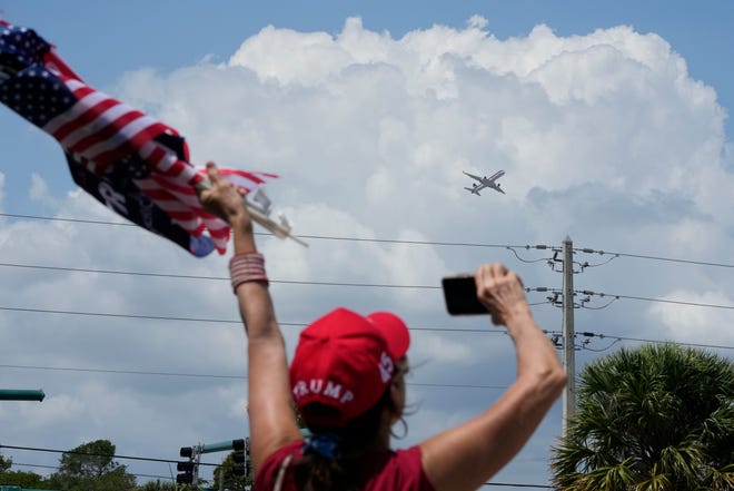 A supporter of former President Donald Trump waves as his jet departs West Palm Beach, Fla., on April 3, 2023.