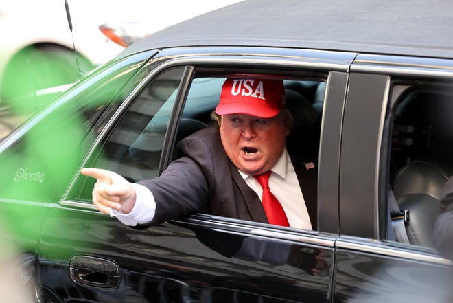 A person dressed as former president Donald Trump rides in a car past Trump Tower on April 4, 2023 in New York City.